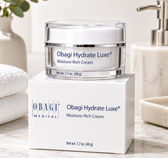 Obagi Hydrate Luxe Moisture-Rich Cream jar on a white box with a bathroom setting.