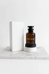 Black perfume bottle labeled 'Ombre Nomade' with a white box and white container in the background.